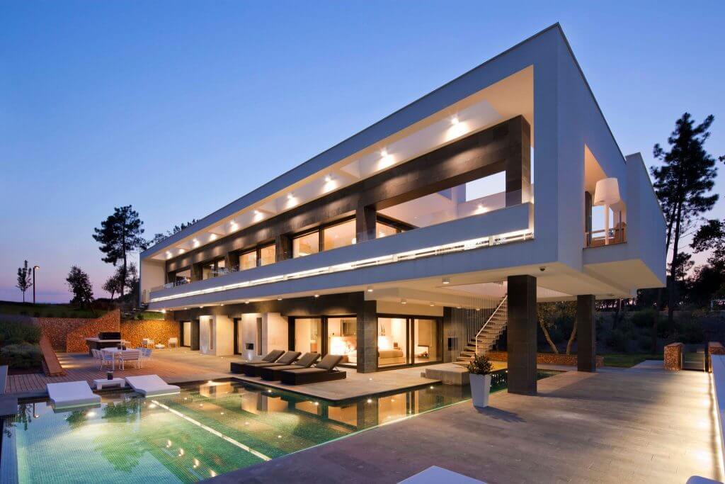A photo of a luxury home with a pool at dusk.