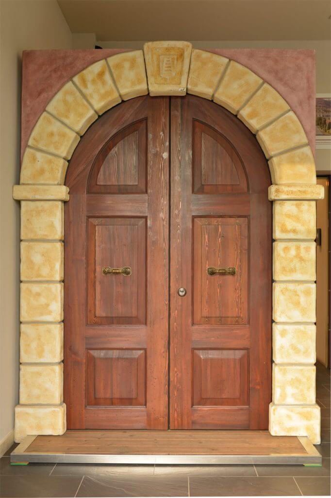 A photo of arched double custom front doors finished with real wood.