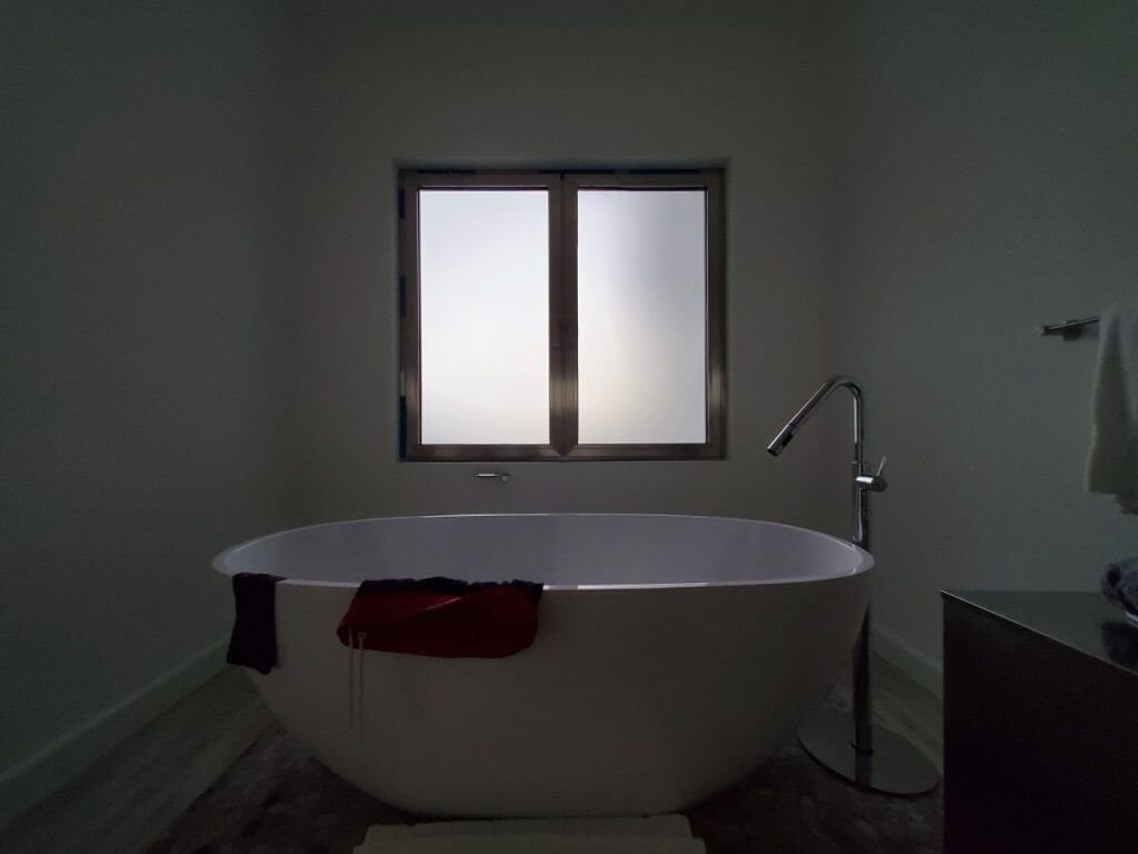 A photo of a large soaker tub in front of a frosted custom security window.