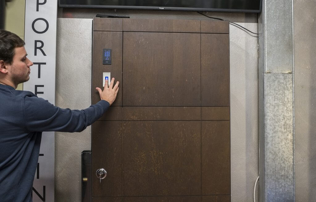 A photo of an Italian artisan testing the fingerprint scan on a custom security door.