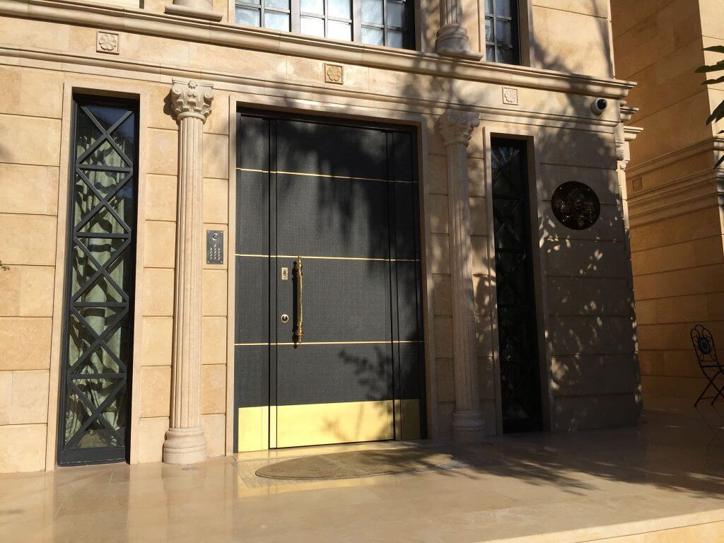 A photo of a large black and gold custom front door for a stately townhome.