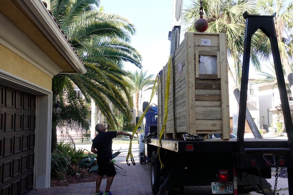A photo of a crane-truck delivering a custom security door to a luxury home.