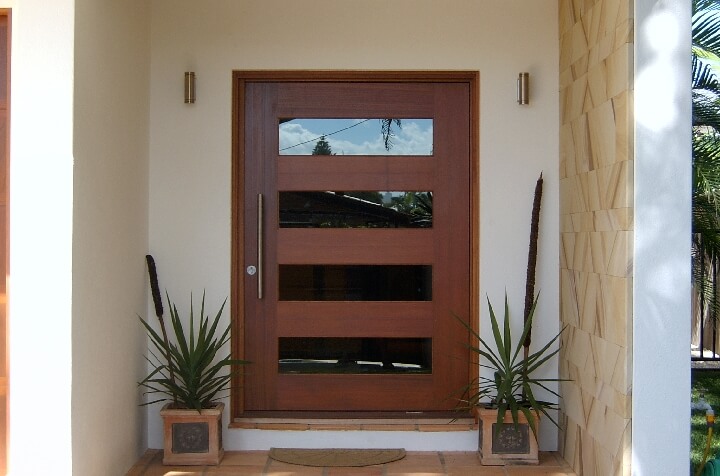 A photo of a large pivot door at the front entrance of a luxury home. 