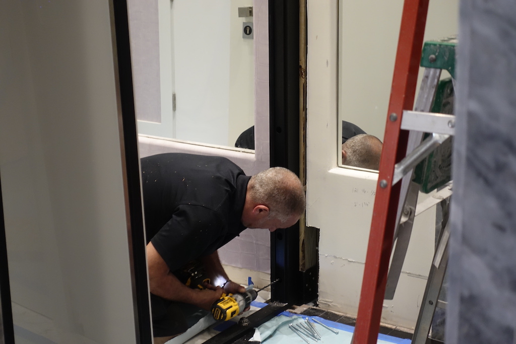 A photo of a contractor installing a custom security door. 