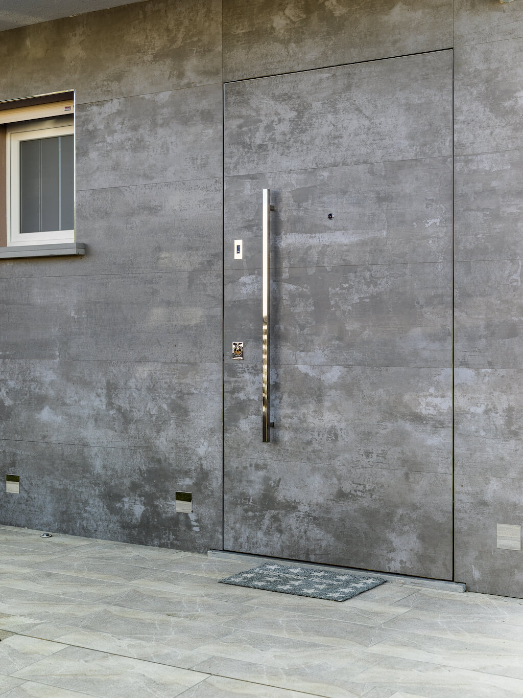 A photo of a front entry frameless door designed to match the exterior wall seamlessly.