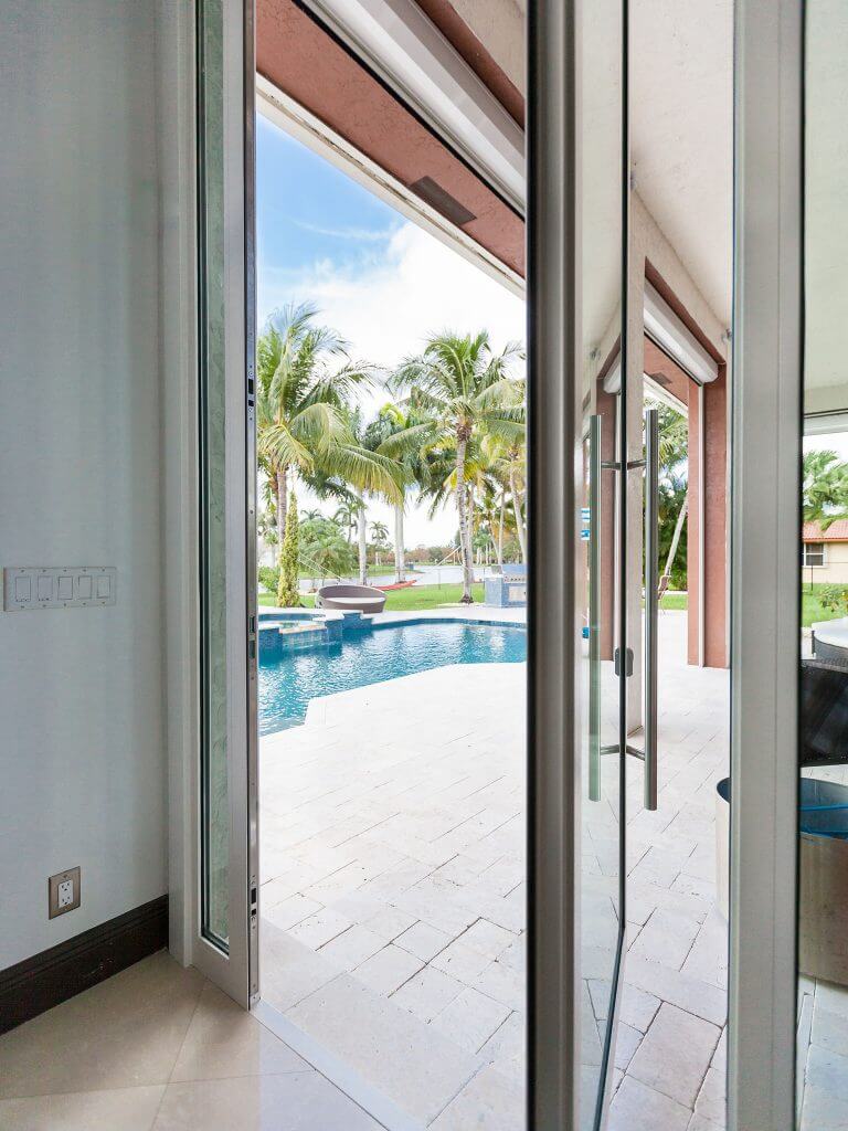 An image of a glass pivot door leading out to a pool.