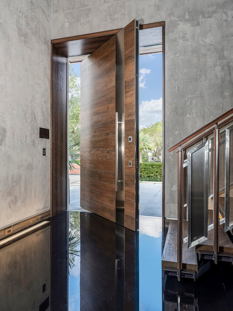 A photo of the interior side of an oversized pivot door from the foyer of a luxury home.