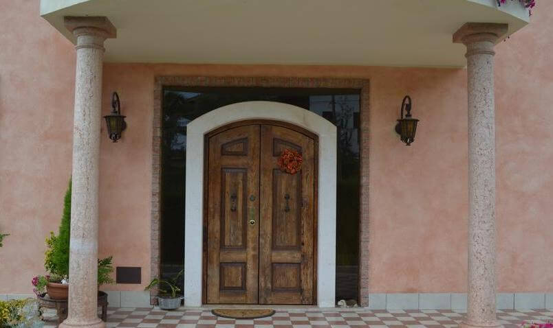 A photo of the front entrance of a luxury home in Italy with solid wood double security doors.