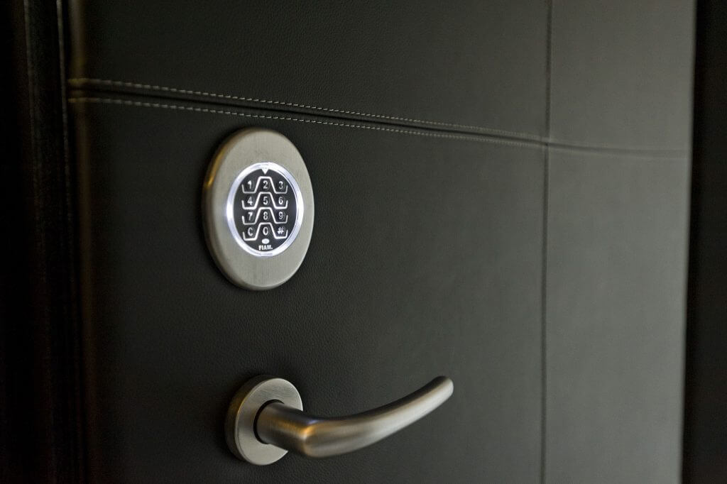A close-up photo of a steel security door finished in hand-stitched Italian leather featuring a keypad lock.