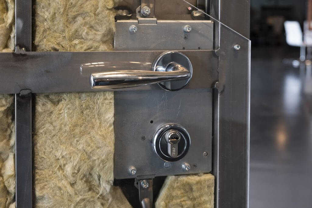 A close-up photo of a lock and handle installed on a partially completed home security door.