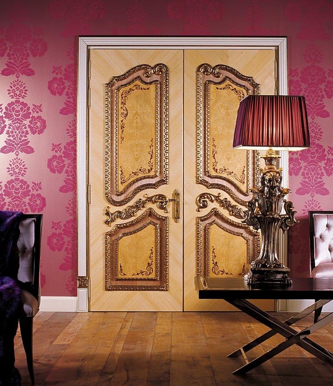 A photo of intricately decorated double wood security doors at the entrance of a master suite.