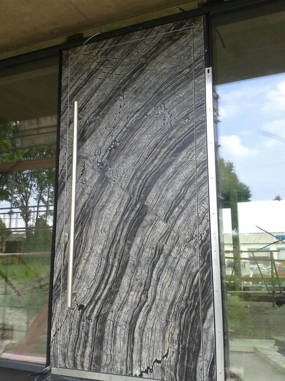 A photo of an oversized security door made with a custom marble covering.
