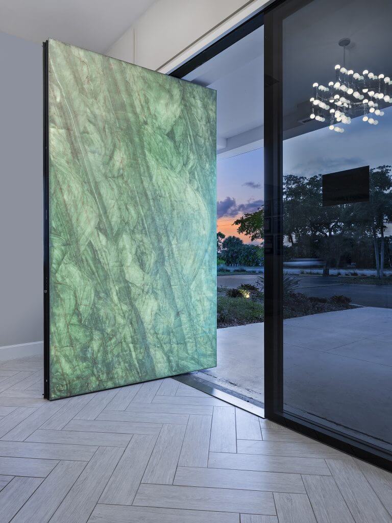 A photo of a large pivot door finished with marble.