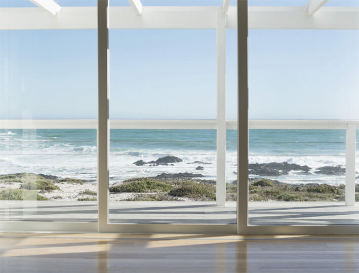A photo of a sliding glass door made from security glass overlooking an ocean view.