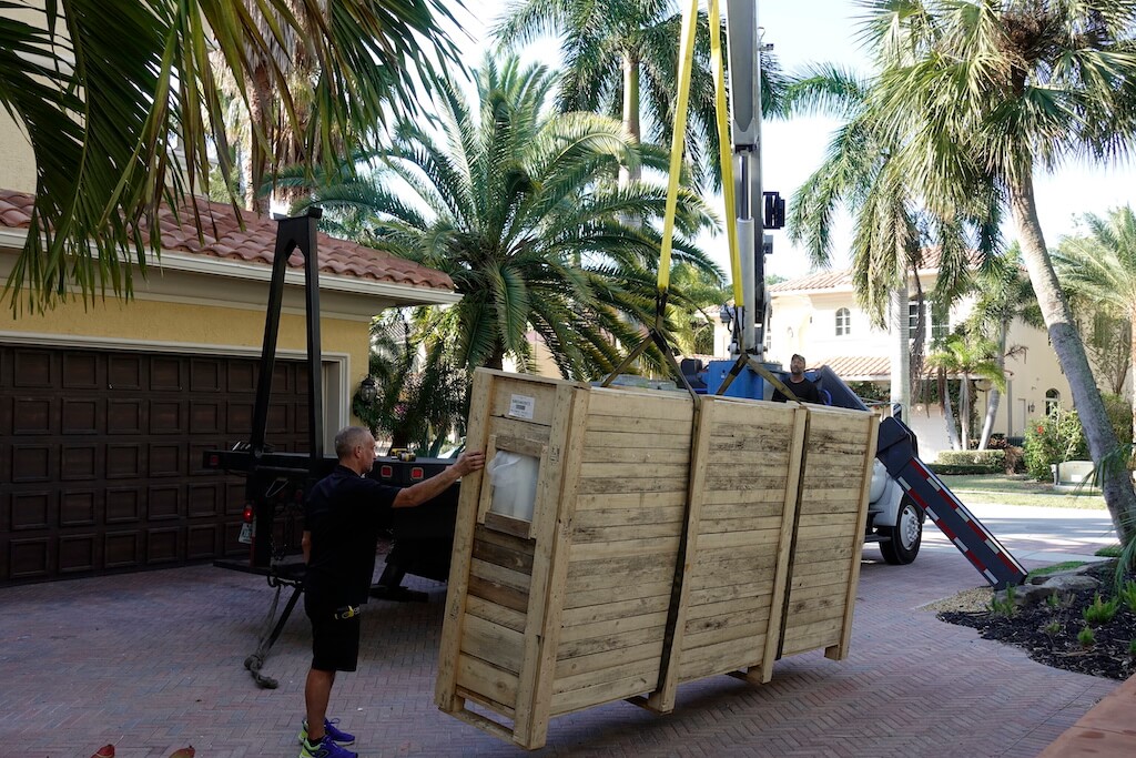 A photo of a work crew taking the crate containing the security door off the truck that transported it.