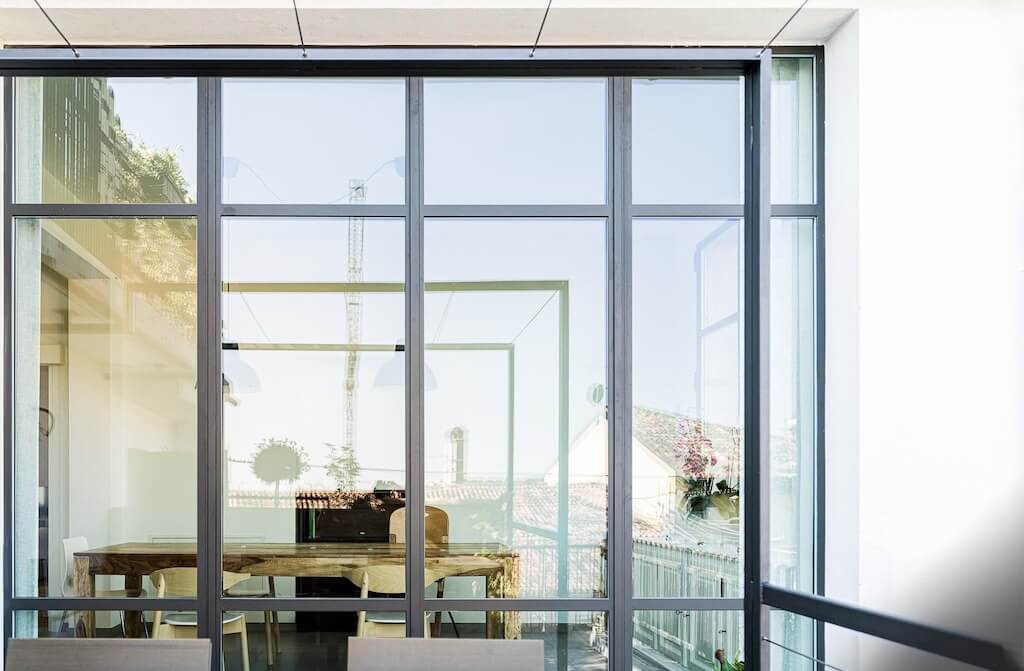 A photo of a window wall made from security glass overlooking an outdoor seating area on a patio.