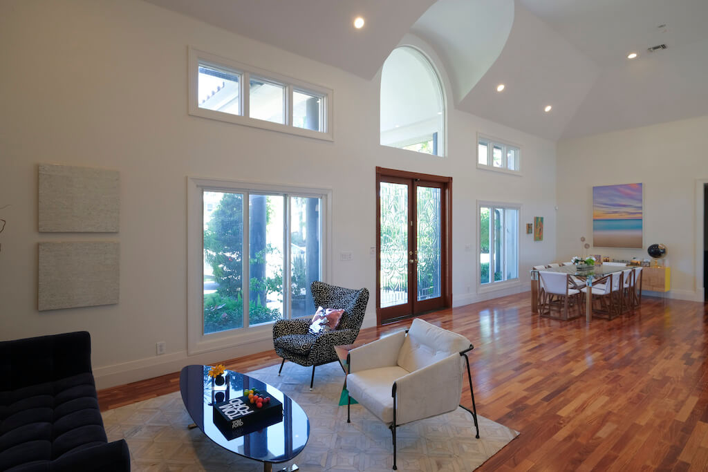 A photo of an open concept living and dining room leading out to a back patio via glass double security doors and large security windows.