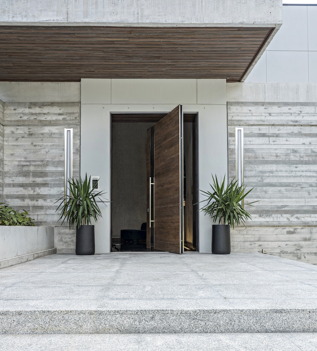 A photo of an oversized pivot door at the front entrance to a luxury home.