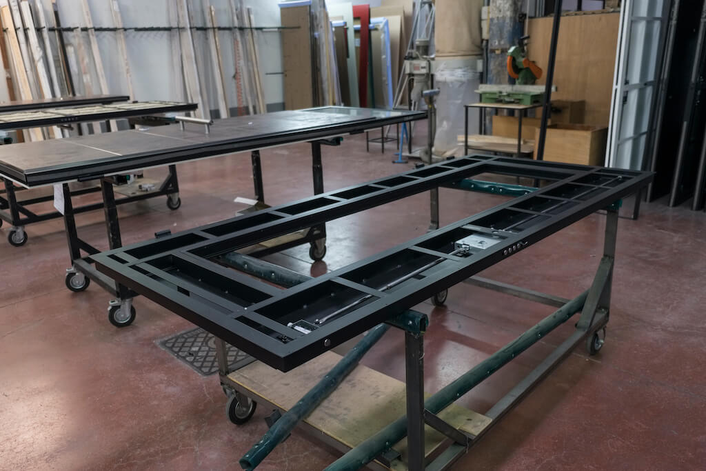 A photo of custom security doors in various states of production, including the plain steel frame and another nearly finished.