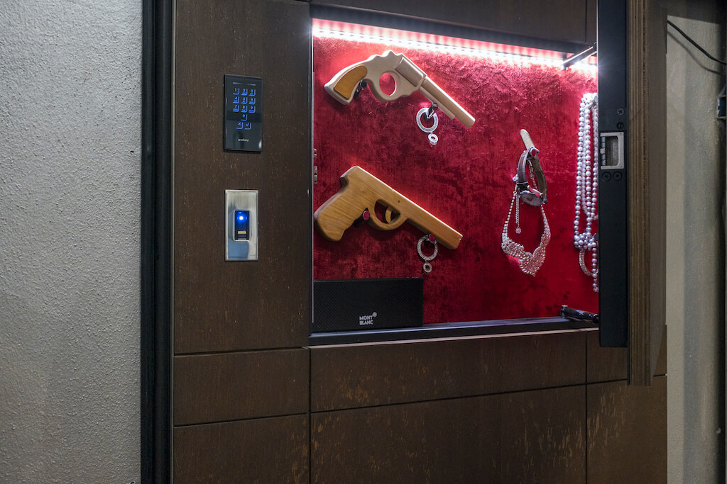 A photo of a hidden compartment in a custom security door containing jewelry and guns.