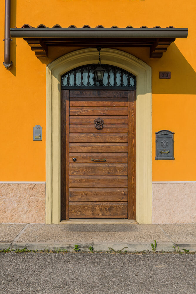 A photo of a steel security door finished with wood and an elegant door knocker.