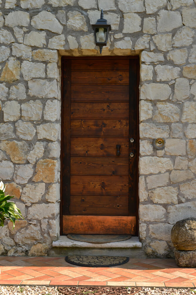 A photo of a steel security door finished with real wood on a stone building.